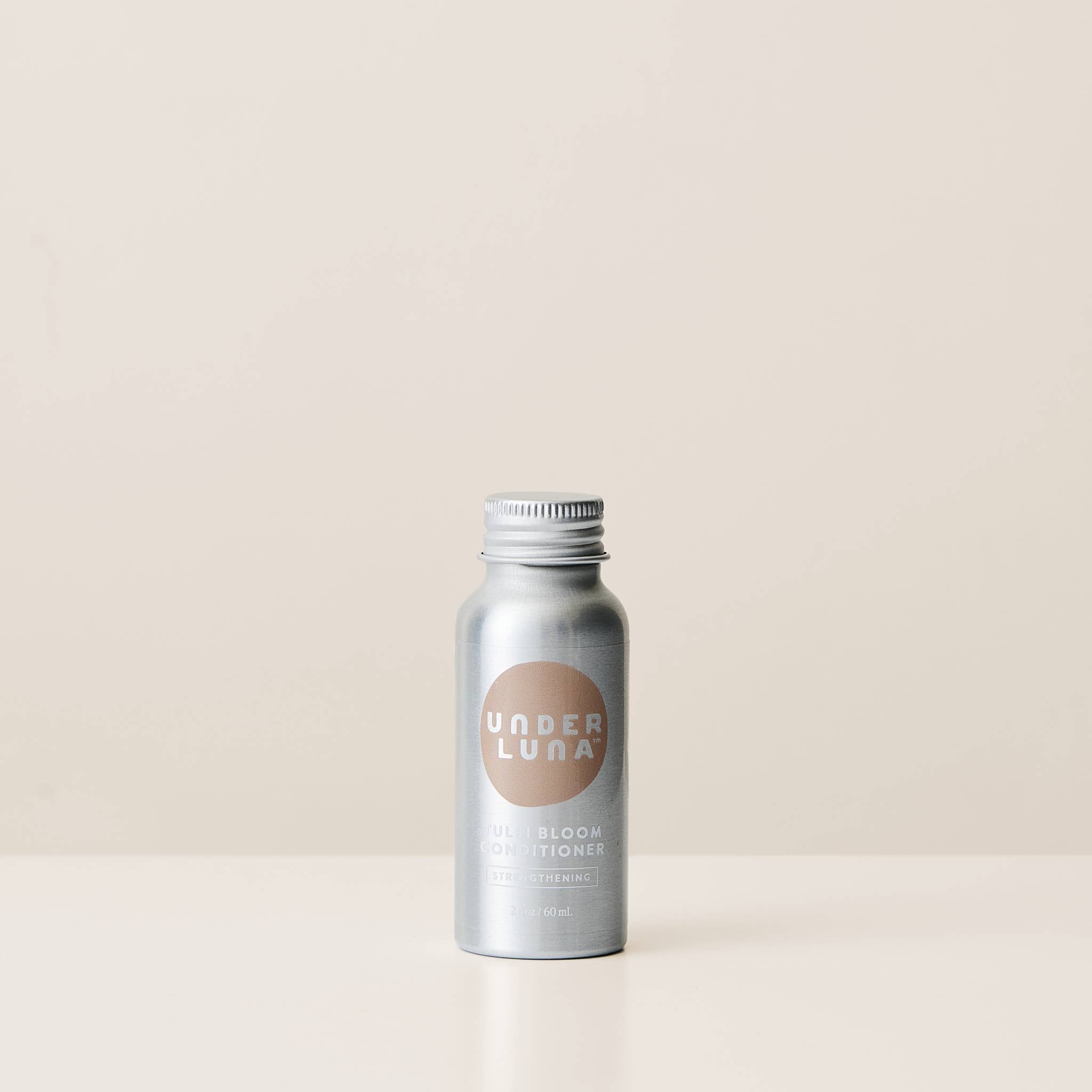 Silver bottle with 'Under Luna' branding on a beige background