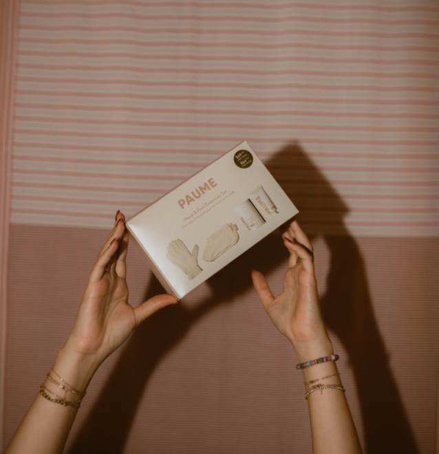 Person holding a 'PAUME' product box against a striped wall.