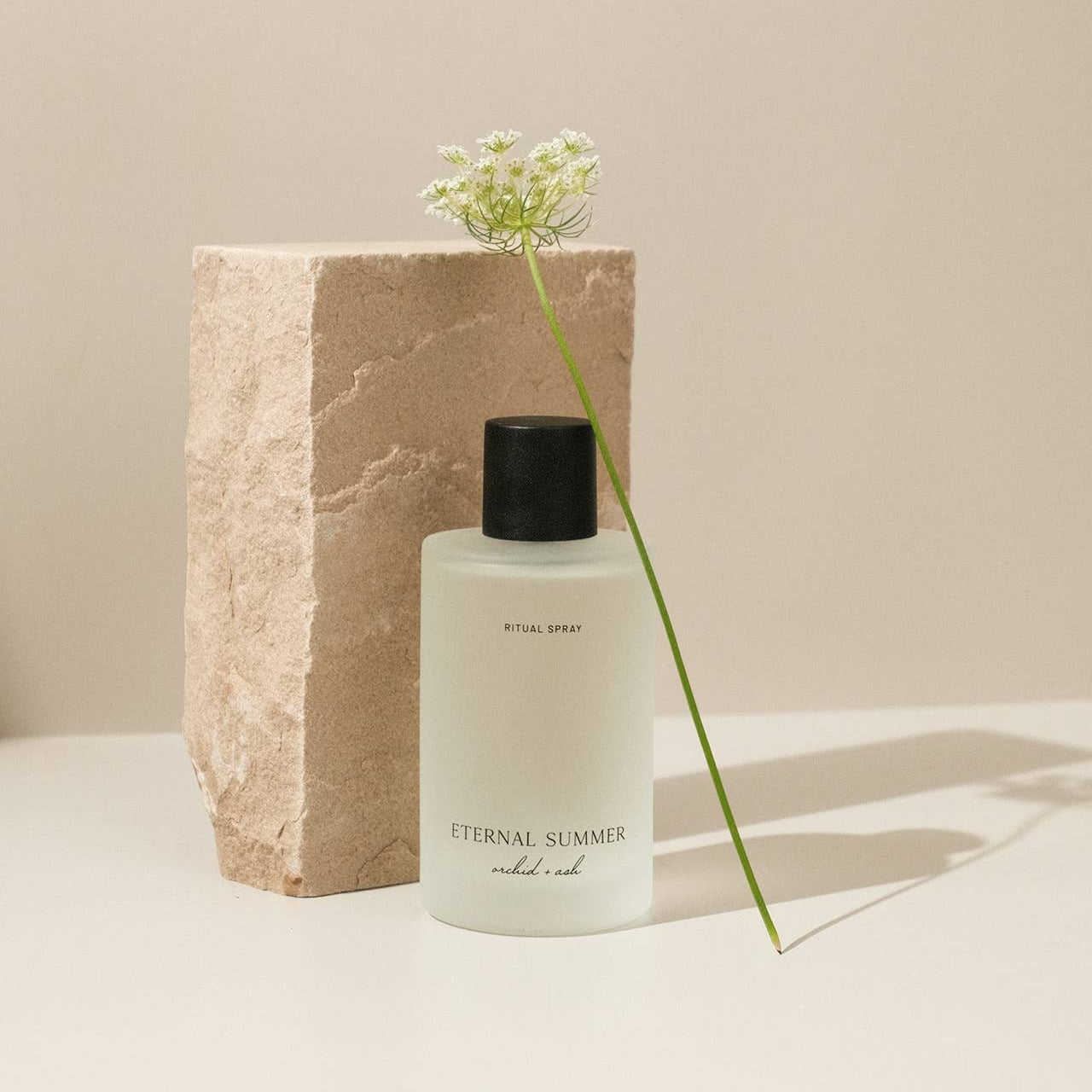 Skincare bottle labeled 'Eternal Summer' with a flower on a neutral background