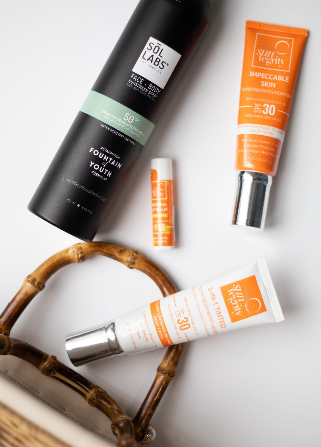 flat lay of nontoxic summer essentials like suntegrity tinted moisturizer spf and lip balm also clear mineral spf