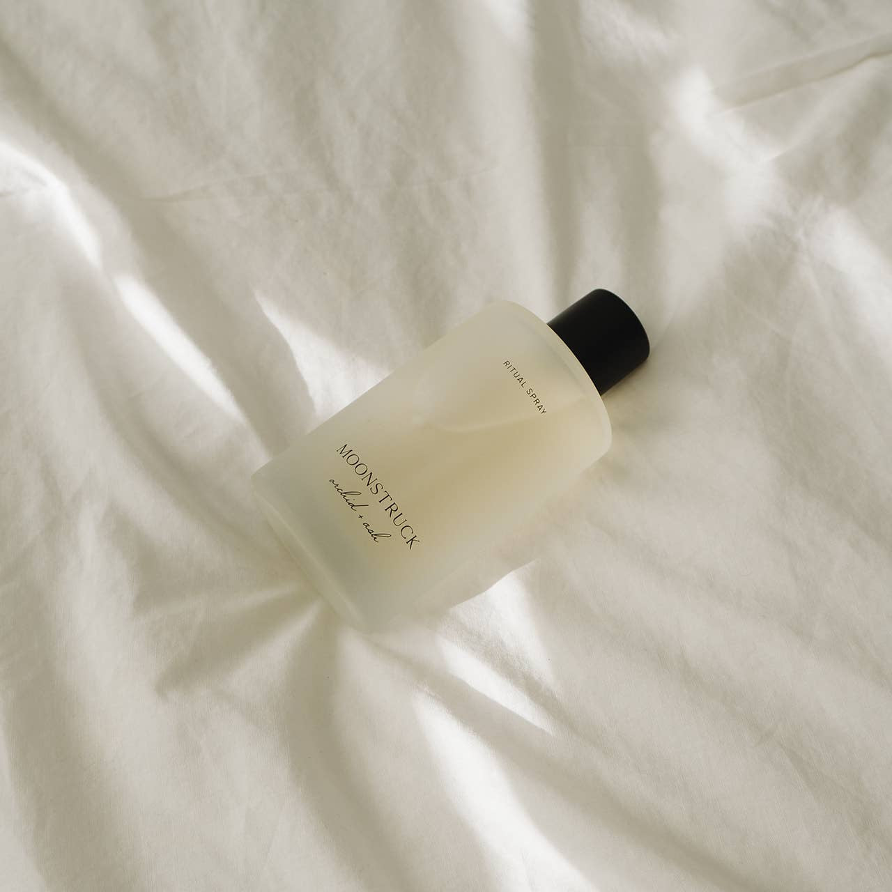 natural body perfume spray bottle on a white textured surface