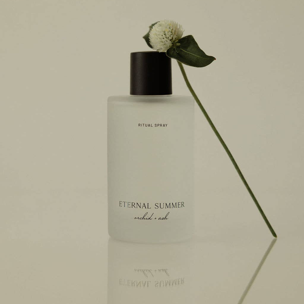 Perfume bottle labeled 'Eternal Summer' with a white flower on a beige background